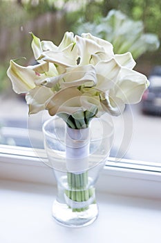 Wedding bouquet of flowers. White Calla lilies. The bouquet is in a glass vase