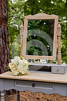 A wedding bouquet in the forest on a table with a mirror. Wedding decorations
