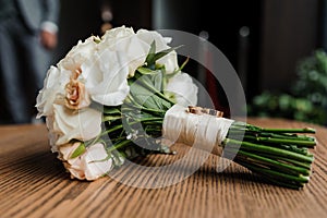 Wedding bouquet of fresh flowers, a pair of gold rings close-up. Wedding details