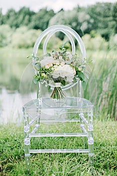 Wedding bouquet on the glass chair, outdoor, fine art.