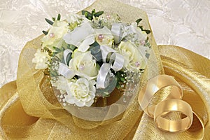Wedding bouquet with gold wedding rings on golden and white background