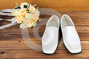 Wedding bouquet with groom's shoes on wood background