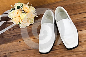 Wedding bouquet with groom's shoes on wood background