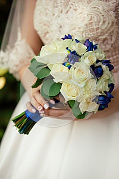 Wedding Bouquet in the hands of the bride. Beautiful flowers on the background of a wedding dress and rings