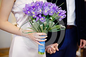 Wedding Bouquet in the hands of the bride. Beautiful flowers on the background of a wedding dress and rings