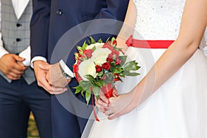Wedding bouquet in hands of bride. The bride and groom in the registry office.