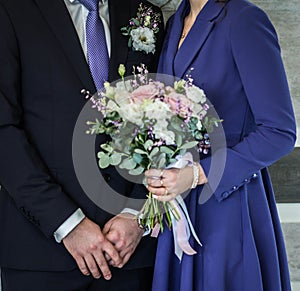 Wedding bouquet in hands of bride and groom, selective focus