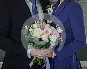 Wedding bouquet in hands of bride and groom, selective focus