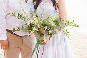 A wedding bouquet is in the hands of newly-wed