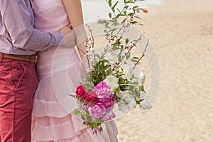 A wedding bouquet is in the hands of newly-wed