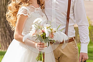 A wedding bouquet is in the hands of newly-wed