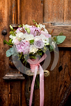 Wedding bouquet hanging on an old door handle on the background of ancient wooden doors. photo