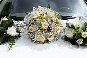 Wedding bouquet lies on the hood of white car