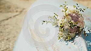Wedding bouquet lies on an old blue boat on the beach, sunny day, light breeze