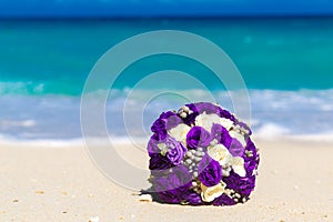 Wedding bouquet lying on the sand on a tropical beach. Blue sea