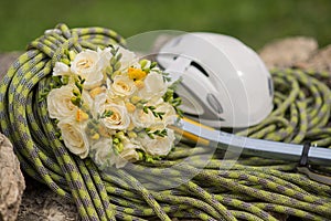 A wedding bouquet made of white roses on a rope with an ice ax