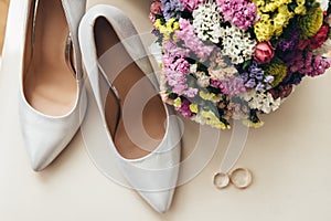 Wedding bouquet near the bride`s shoes and wedding rings