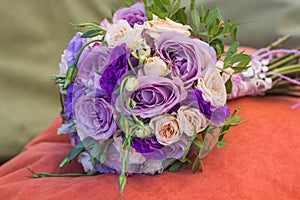 Wedding bouquet on an orange pillow, bouquet of bride from rose cream spray, rose bush, rose purple Memory Lane, violet eustoma, e