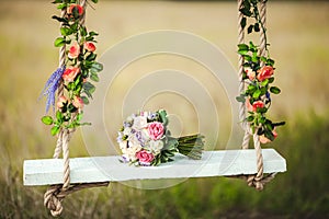 Wedding bouquet of peonies lying on white bench swing decorated with fresh flowers.