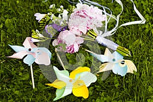 Wedding bouquet of pink, violet and blue flowers and three decorative paper windmills