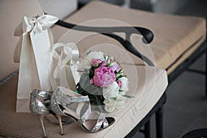 Wedding. Bouquet of pink, white flowers and greenery is in a chair against next to the bride`s shoes