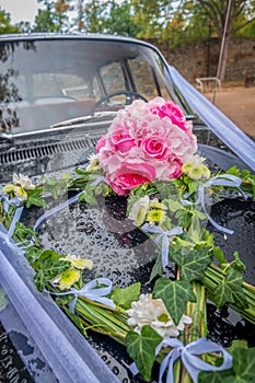 Wedding bouquet and rings on the hood of the vehicle