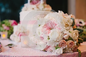 Wedding bouquet of roses in front of wedding cake.