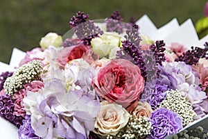 Wedding bouquet of tree pink peony, purple carnations, blue hydrangea, lilac, wrapped in craft paper