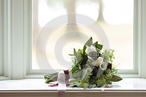 Wedding bouquet with vintage ribbon on a window sill with shallow depth of field