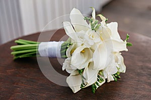 A wedding bouquet of white flowers lies on a round table