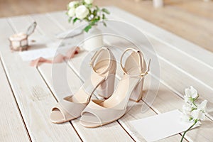 Wedding bouquet of white flowers, shoes and wedding rings on a wooden background.