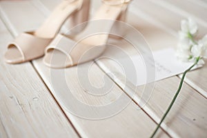 Wedding bouquet of white flowers, shoes and wedding rings on a wooden background.