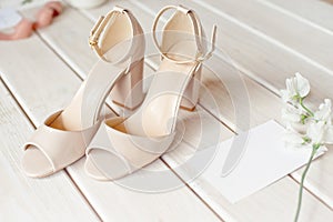 Wedding bouquet of white flowers, shoes and wedding rings on a wooden background.