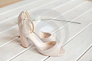 Wedding bouquet of white flowers, shoes and wedding rings on a wooden background.