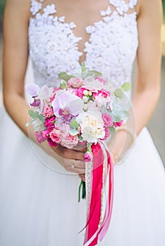 Wedding bouquet of white and pink lowers in the hands of the bride