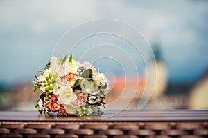 Wedding bouquet of white and pink peonies lies on a table on the background of the city view