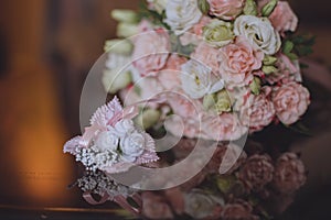 Wedding bouquet of white and pink roses. The bouquet and boutonniere are on the glass table