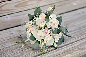 Wedding bouquet of white and pink roses on a wooden bench
