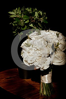 Wedding bouquet of white roses on a table in harsh light