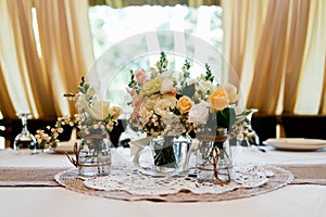 Wedding bouquets of yellow, white and pink roses are in vases