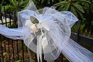 A wedding bow hangs on an outside fence.