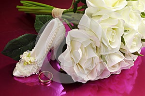 Wedding bridal bouquet of white roses with shoe and ring.