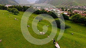 Wedding. The bride and groom are run along the green grass against the backdrop of the mountains