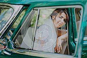 Wedding bride rest and have fun on green vintage retro car after wedding. Honeymoon concept. Car woman happy in old