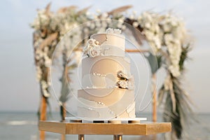 Wedding cake at a beach wedding on the background of a beautiful arch for an exit ceremony