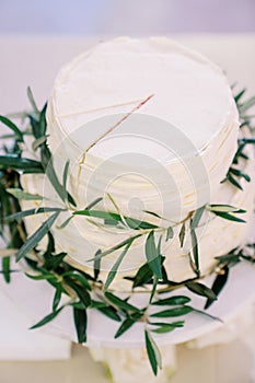 Wedding cake with a cut sector stands on a tray on the table. Top view