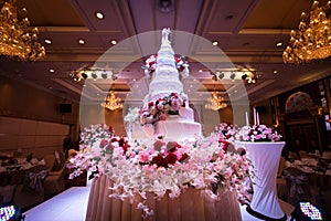 Wedding cake and flowers decorations with chandelier on ceiling.