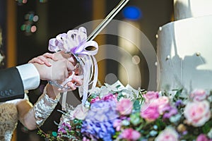 Wedding cake. gorgeous bride and stylish groom cutting stylish wedding cake with flowers at wedding reception in restaurant.