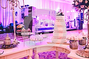 WEDDING CAKE AT IMPRESSIVE VIOLET VENUE WITH BEAUTIFUL CANDY TABLES, FLORAL GREEN DECORATION, BLURRED BACKGROUND, YELLOW LI
