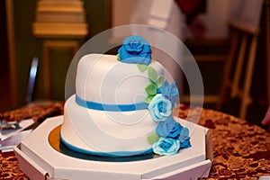 Wedding cake in white frosting with blue and turquoise roses.